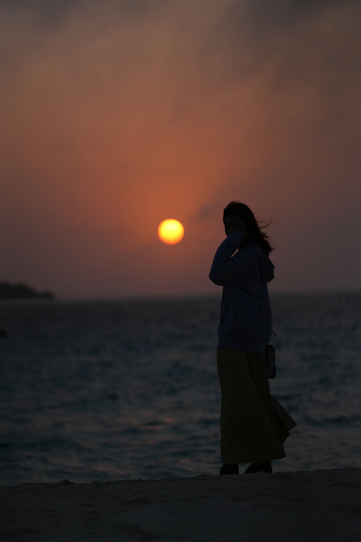 夕日の海辺に立つAyaco